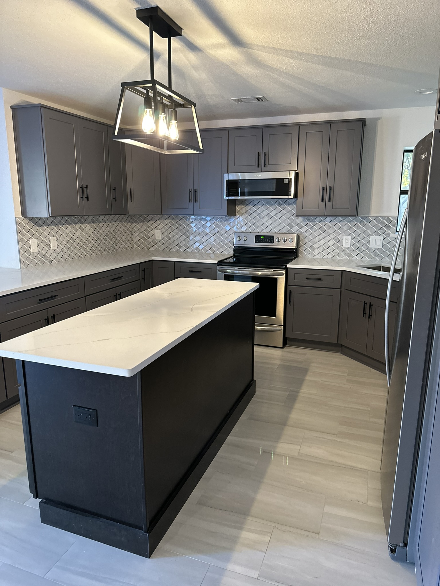 Modern kitchen remodel with grey shaker cabinets, black island and quartz countertop