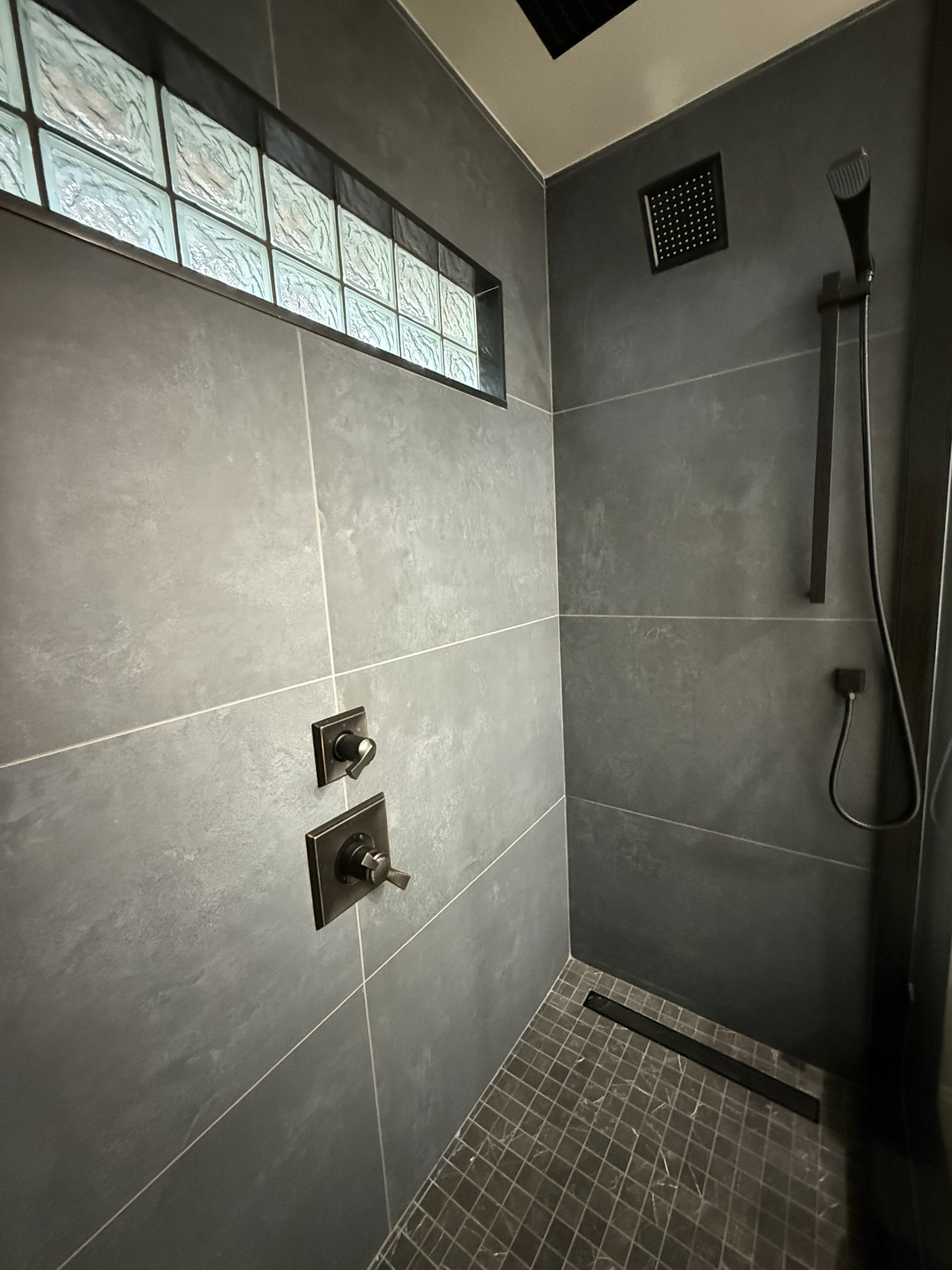 Dark grey tile walk-in shower with glass block window